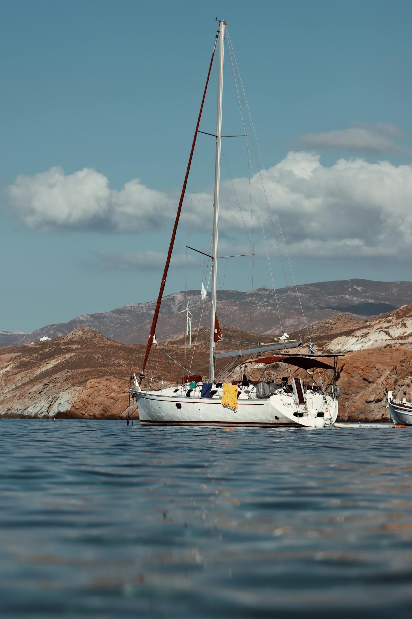 Serene view of a sailing yacht anchored off the rocky coast of Naxos in the Aegean Sea, Greece.